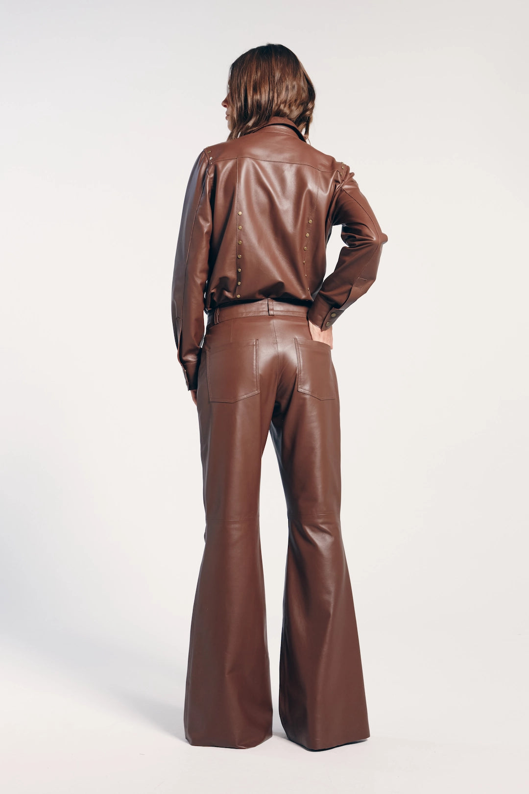 Calça flare marrom couro vista de trás. Ideal para destacar a silhueta, adicionando um toque sofisticado a qualquer look.