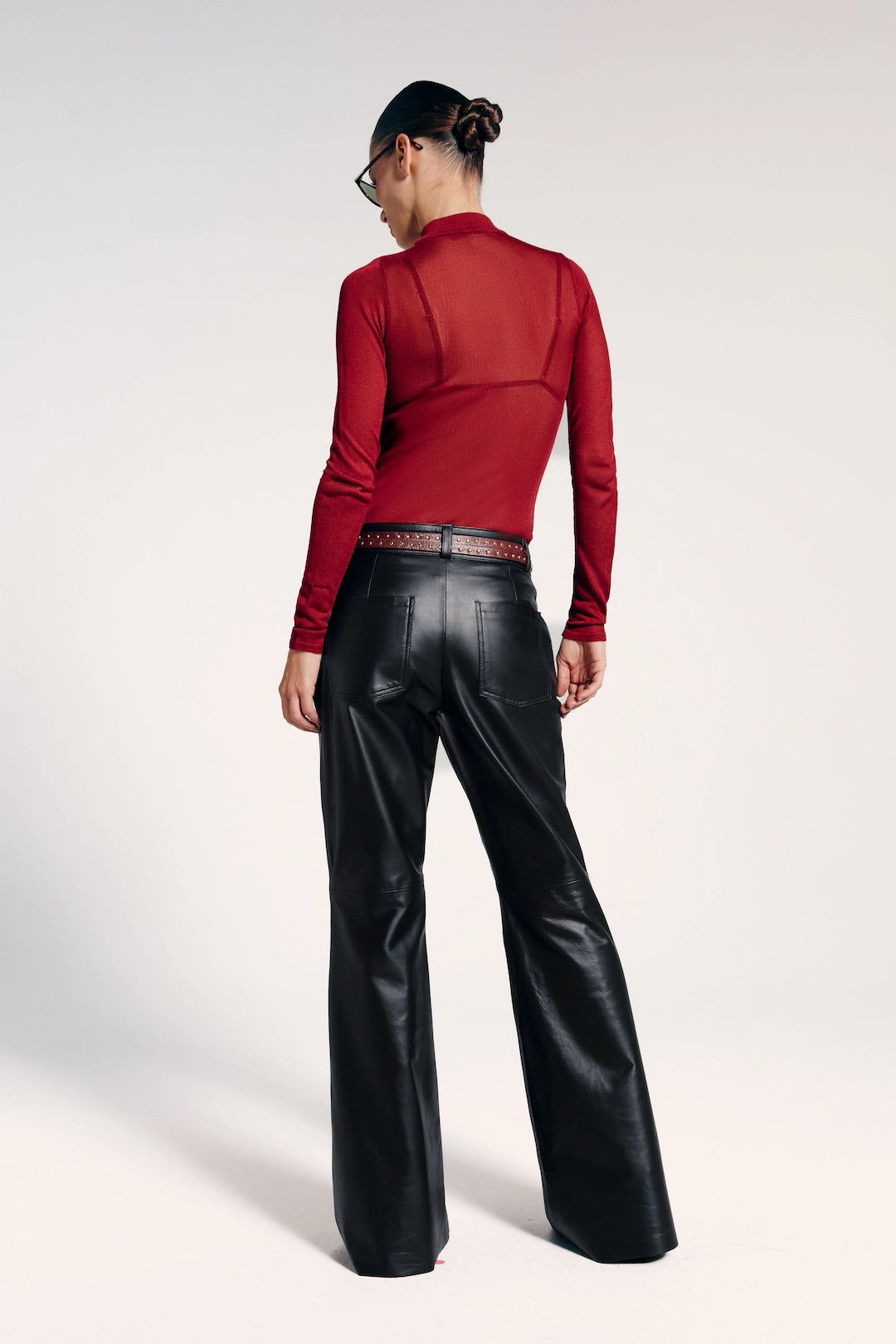 Calça flare de couro preta vista de trás, destaca-se por seu estilo sofisticado e moderno.