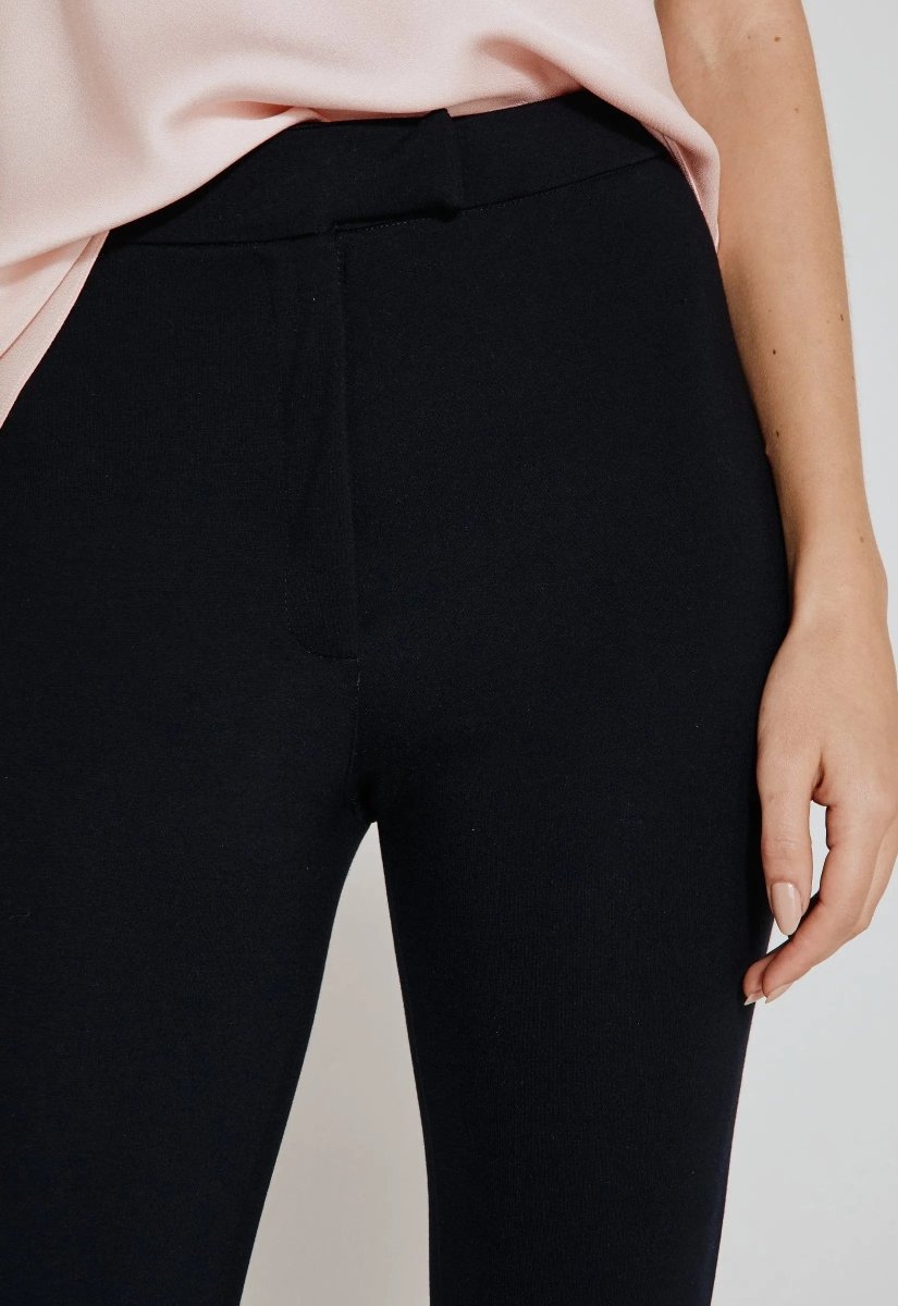 Close da calça legging preta feminina com pezinho, cintura alta, ajustada ao corpo, combinada com blusa de cetim rosa claro.