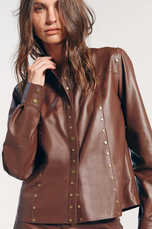 Jaqueta couro marrom com tachas, estilo arrojado e moderno. Perfeita para adicionar um toque de atitude ao look, destacando-se pela combinação de elegância e ousadia.