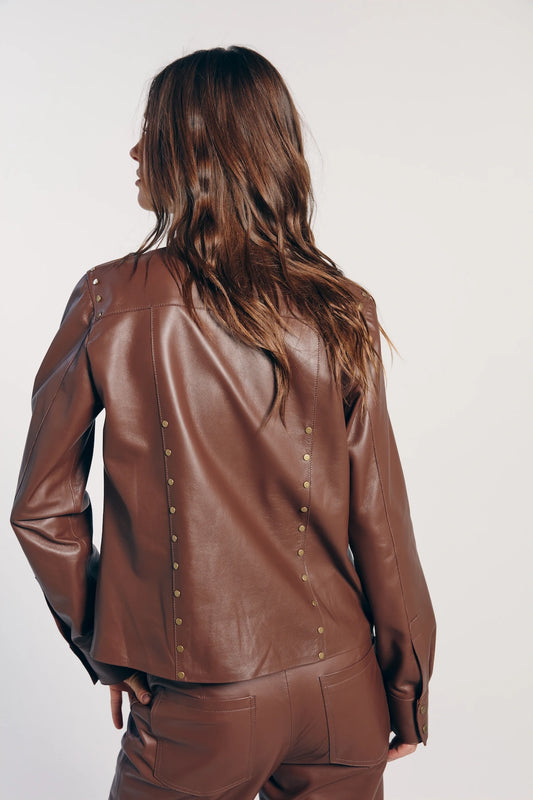 Jaqueta couro marrom tachas vista de costas, combinando estilo e atitude. Ideal para um visual descolado, seu design elegante e detalhes metálicos agregam personalidade.