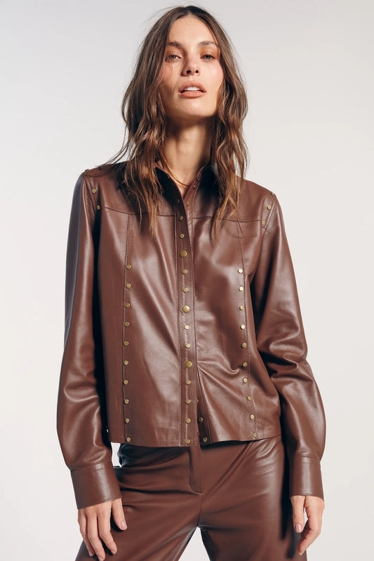 Jaqueta couro marrom tachas, destacando-se pelo estilo moderno e ousado. Ideal para compor looks autênticos, acrescentando um toque de atitude e elegância.