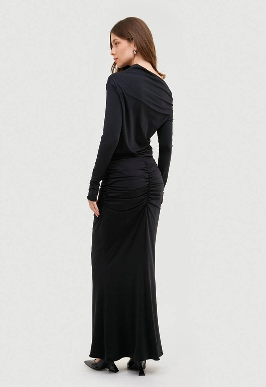 Saia longa preta drapeada, design elegante e fluido. Modelo combina a peça com blusa no mesmo estilo e salto preto.