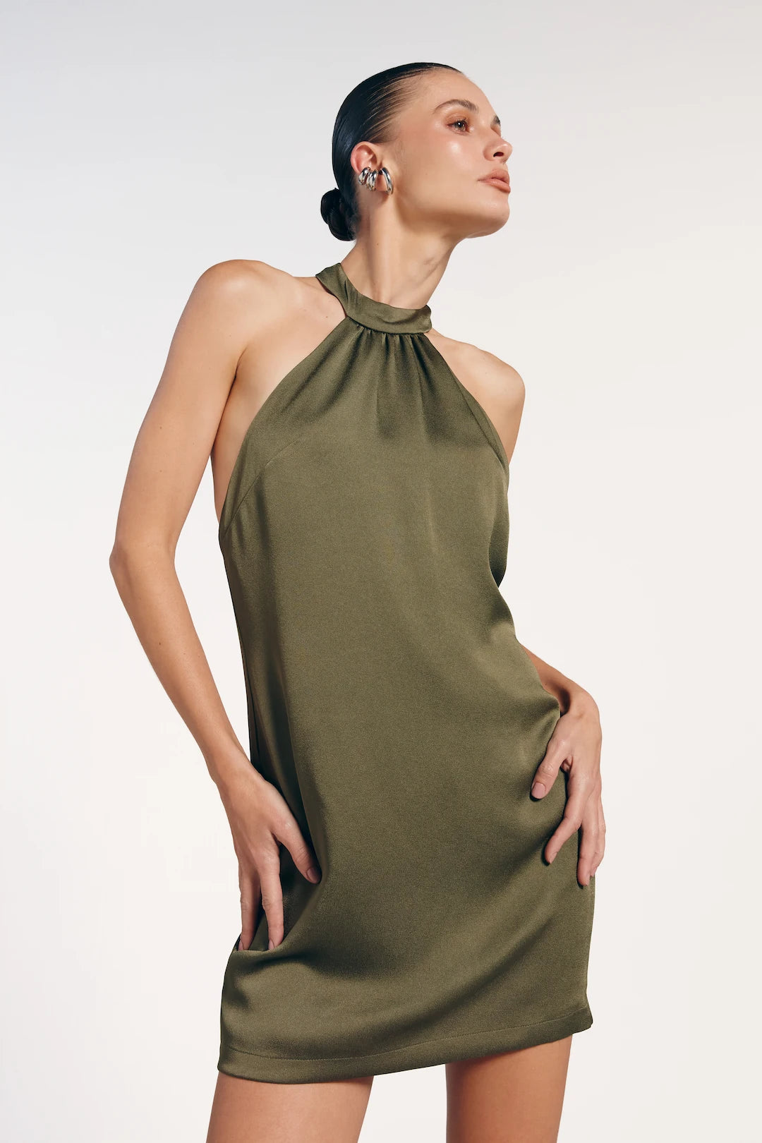 Vestido curto verde oliva com fechamento no pescoço. A peça é frente única.