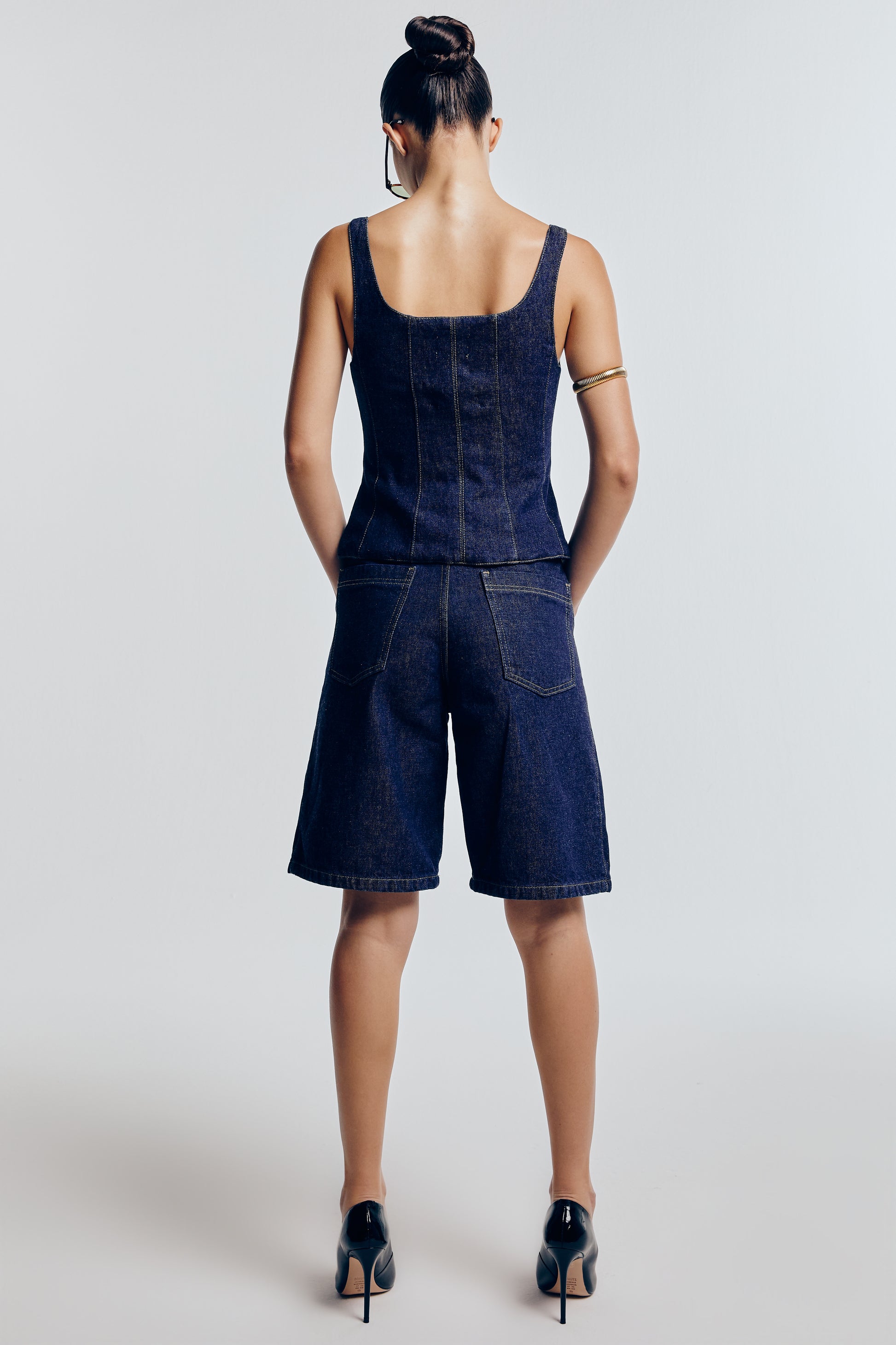 Bermuda jeans azul marinho vista de trás. É prática e moderna, perfeita para um visual casual e confortável.