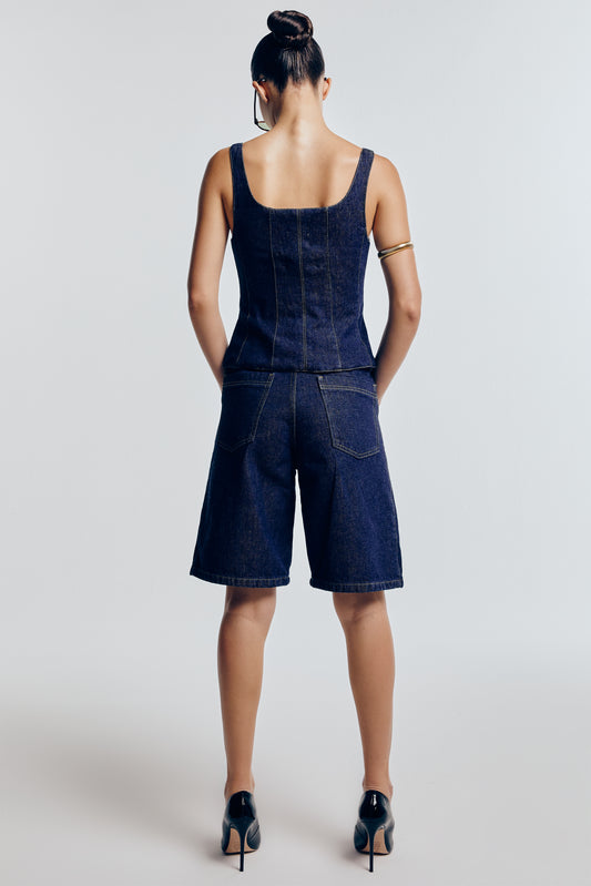 Bermuda jeans azul marinho vista de trás. É prática e moderna, perfeita para um visual casual e confortável.