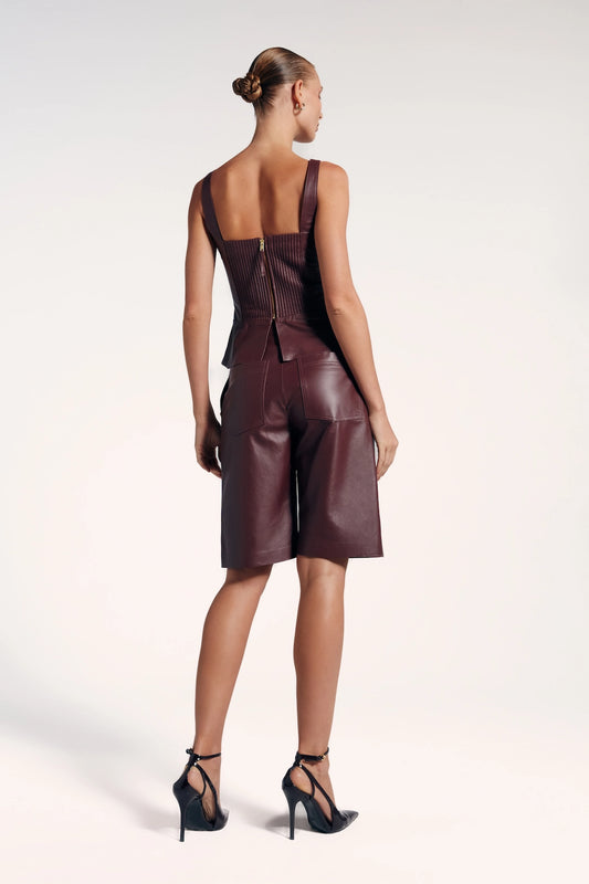 Bermuda marsala couro vista de trás, possui bolsos e é moderna e elegante. Ideal para look sofisticado e ousado.