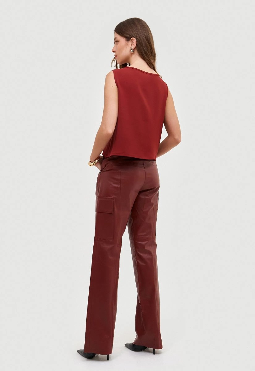 Calça cargo couro bordô com bolsos utilitários e corte reto, peça combinada com blusa vermelha.