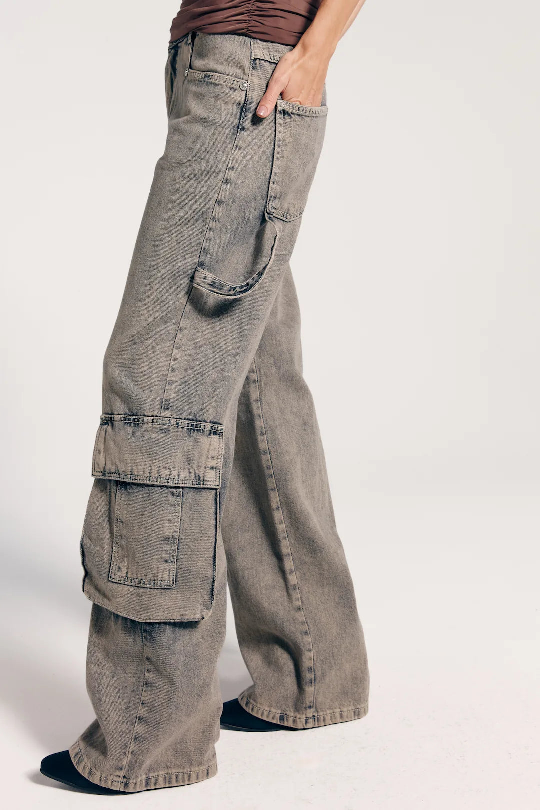 Close da calça cargo jeans estonada, despojada e funcional. Apresenta bolsos diversos.