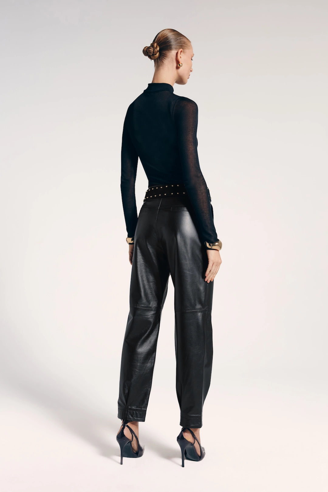 Calça flare de couro preta vista de trás, destaca-se por seu estilo sofisticado e contemporâneo.