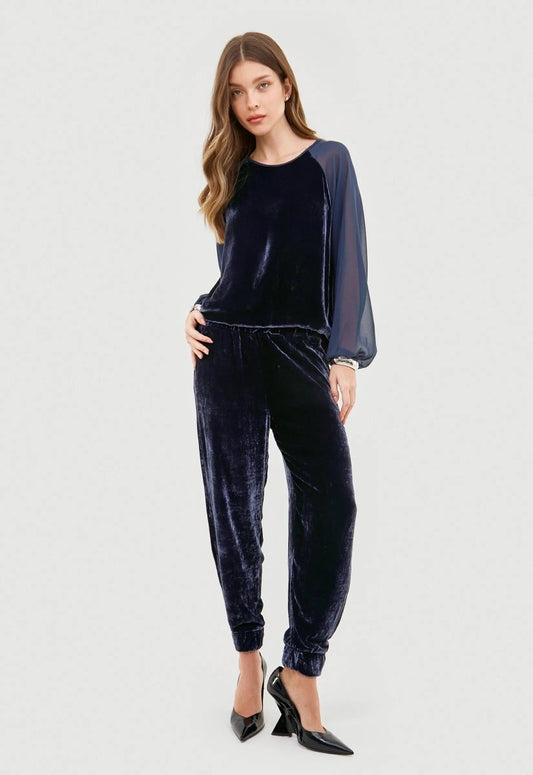 Calça feminina em veludo azul combinada com blusa no mesmo estilo e salto preto.