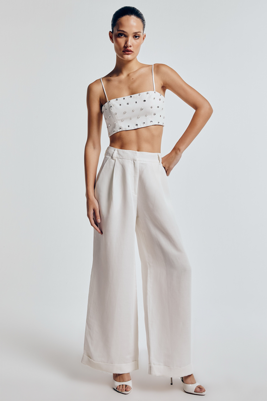 Modelo usando calça wide leg linho off white, cintura alta, pernas amplas e bolsos laterais, combinada com salto alto branco.