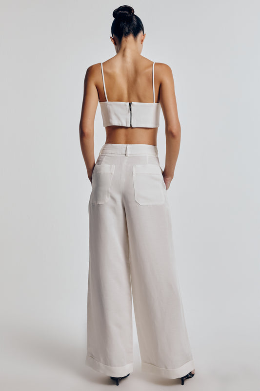 Calça wide leg linho off white vista de trás, cintura alta, pernas largas e bolsos traseiros, transmitindo elegância e conforto.