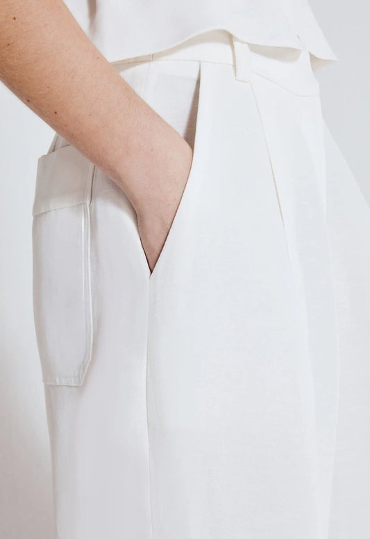 Close da calça wide leg linho off white, com bolso lateral, cintura alta e pregas sutis no design, destacando elegância e leveza do tecido.