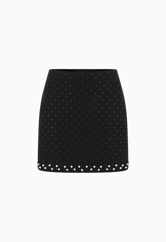 Mini saia com brilho decorada com tachas prateadas. O fundo branco destaca a elegância da peça.