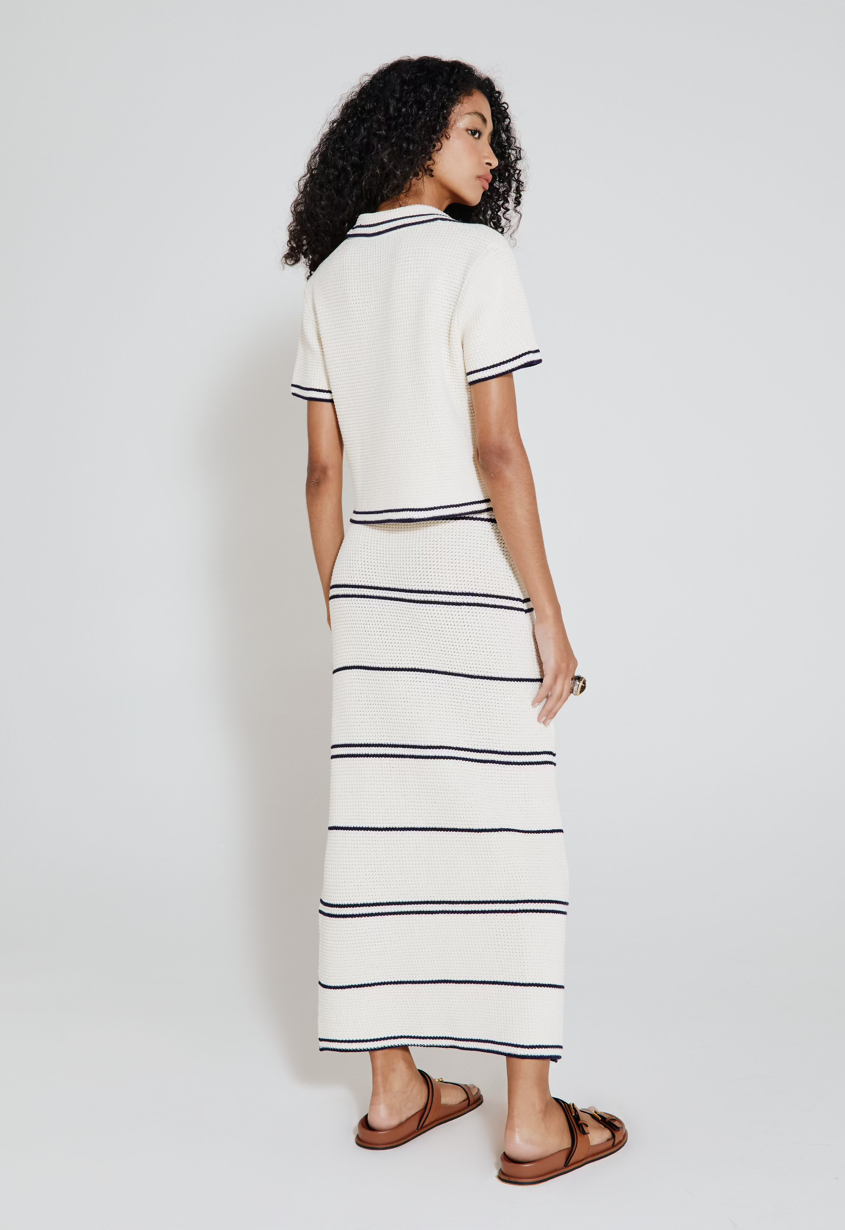 Saia listrada tricot off white vista de trás. A modelo combina a peça com blusa no mesmo estilo.