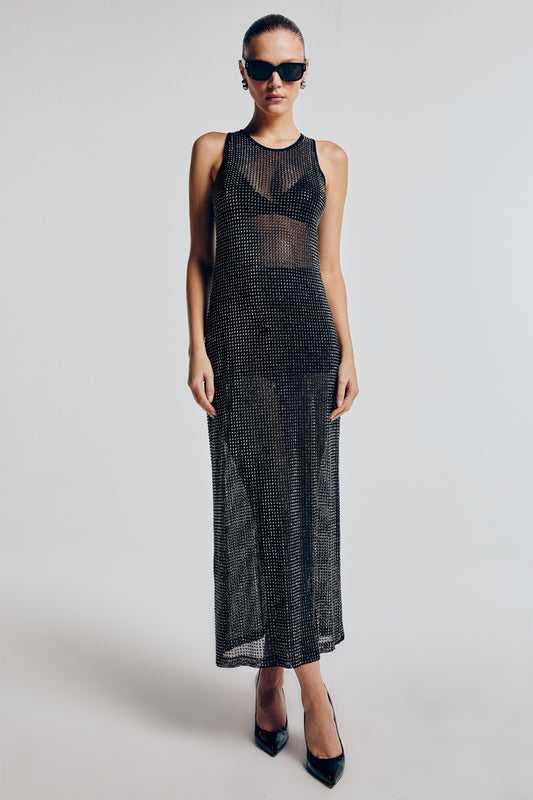 Modelo vestindo vestido longo tule cristais. A peça é combinada com salta preto e óculos escuros. Look moderno e sofisticado.
