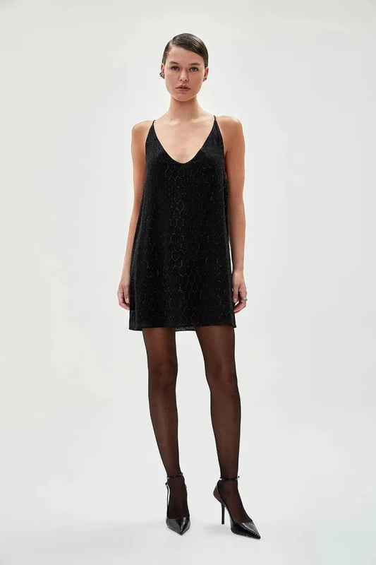Modelo vestindo vestido curto preto com cristais no formate de losango. A peça possui decote em V e modelagem leve e solta.