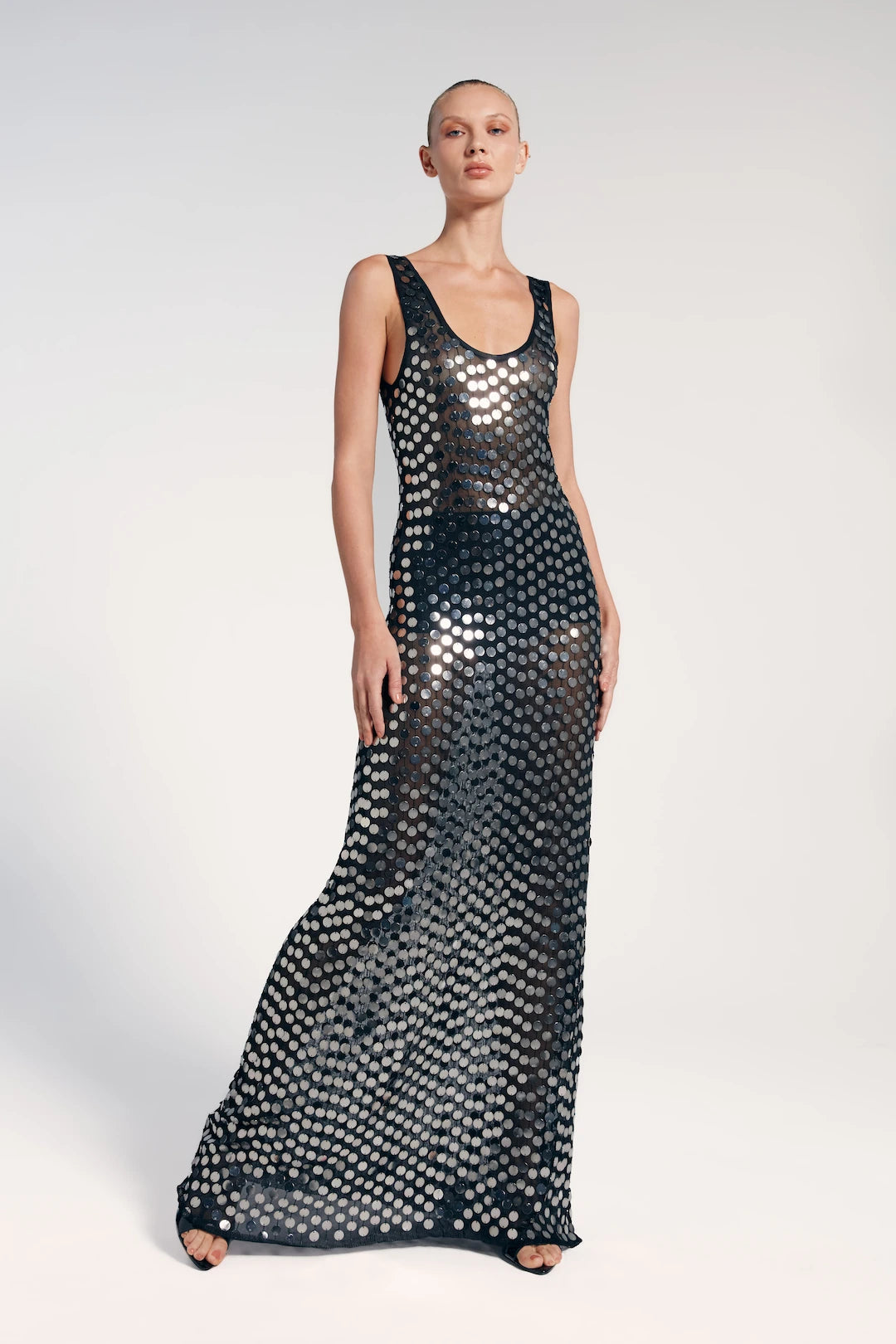 Modelo veste vestido longo paetê preto, elegante e sofisticado com leve transparência